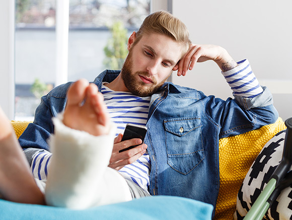 Young adult man with foot in a cast